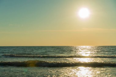 Güneş, gökyüzü, deniz, dalgalar. Güneş gün batımından önce denizde parlar. Deniz ve güneşin güzel fotoğrafı.