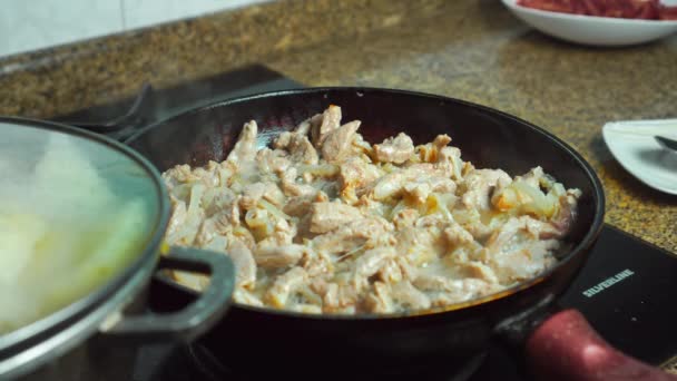 Kawałki mięsa wieprzowego z posiekaną cebulą podczas smażenia na starej patelni — Wideo stockowe