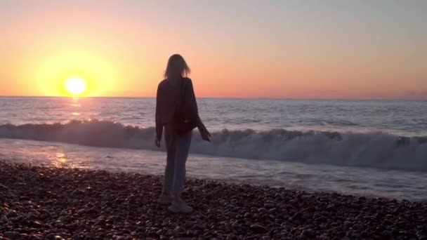 Дівчина стоїть біля моря і мріє. Романтична прогулянка вздовж прекрасного берега. хвилі море . — стокове відео