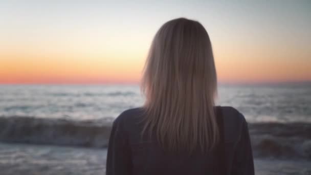 Flickan står vid havet och drömmer. Romantisk promenad längs vackra stranden. vågor hav. — Stockvideo