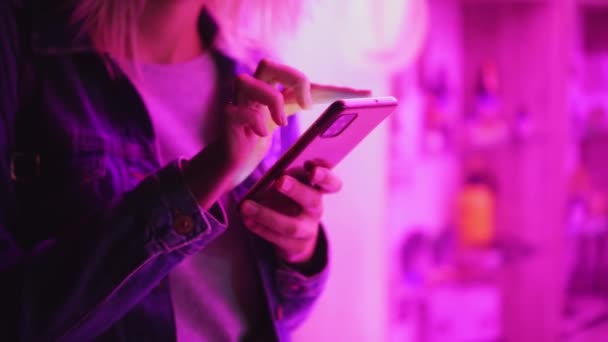 Usando um telefone celular em uma luz de néon brilhante. Cor rosa brilhante criativo. — Vídeo de Stock
