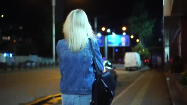 Widok z tyłu młoda stylowa kobieta w dżinsowej kurtce spaceru przez centrum miasta — Wideo stockowe