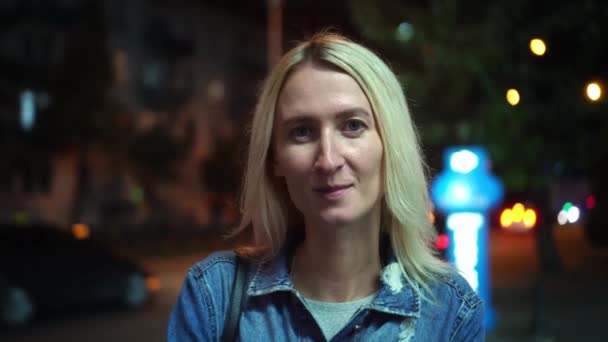 Portret van een mooie stijlvolle blonde die glimlacht naar de camera. Nachtstad — Stockvideo