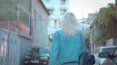 Kot ceketli, şık bir sarışının şehir merkezinde yürüyüşü.