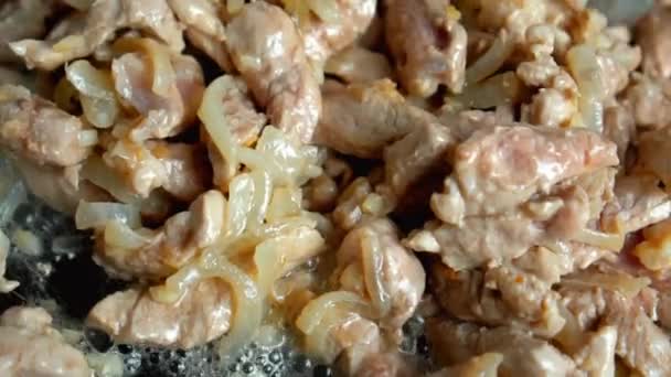 Кусочки свинины с нарезанным луком во время жарки в старой сковородке — стоковое видео