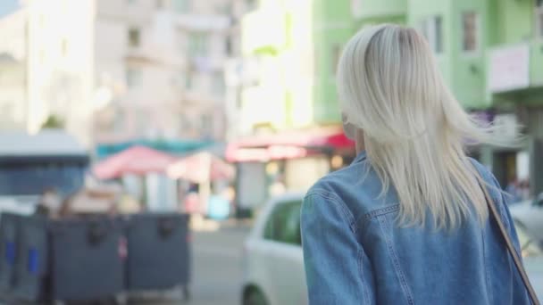 Bakifrån av ung elegant kvinna i denim jacka promenader genom stadens centrum — Stockvideo