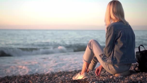 Flickan sitter vid havet och drömmer. Romantisk promenad längs vackra stranden. — Stockvideo