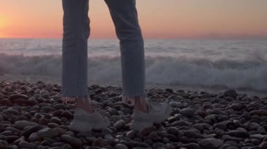 Kız denizin kenarında yürür ve hayal kurar. Yüzü olmayan bacakların yakın çekimi..