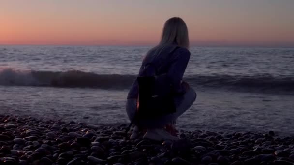 少女は海に座って夢を見ている。美しい海岸沿いのロマンチックな散歩. — ストック動画