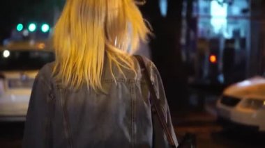 Kot ceketli, şehir merkezinde yürüyen şık bir kadının arka görüntüsü.