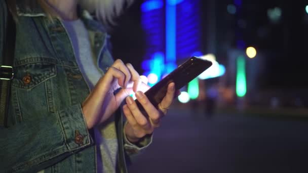 Kadınlar gece haberleşmek için akıllı telefon kullanırlar. arkaplan gökdelenlerine karşı — Stok video