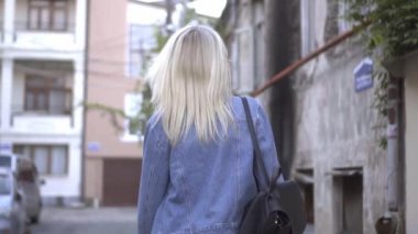 Kot ceketli, şık bir sarışının şehir merkezinde yürüyüşü.