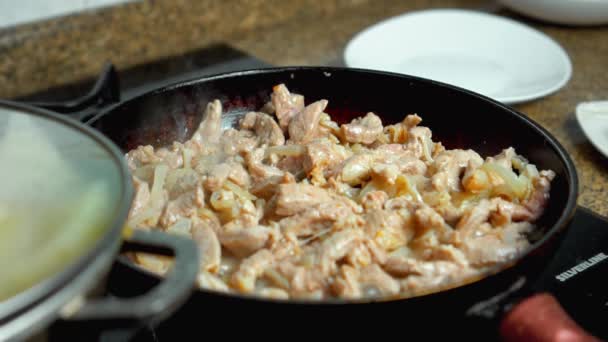 Trozos de carne de cerdo con cebolla picada durante la fritura en una sartén vieja — Vídeo de stock