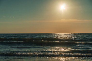 Güneş, gökyüzü, deniz, dalgalar. Güneş gün batımından önce denizde parlar. Deniz ve güneşin güzel fotoğrafı.