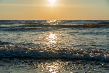 Gün batımında denizde dalgaların yakın çekimi, güneş ışığı yolu. Güzel doğal arkaplan