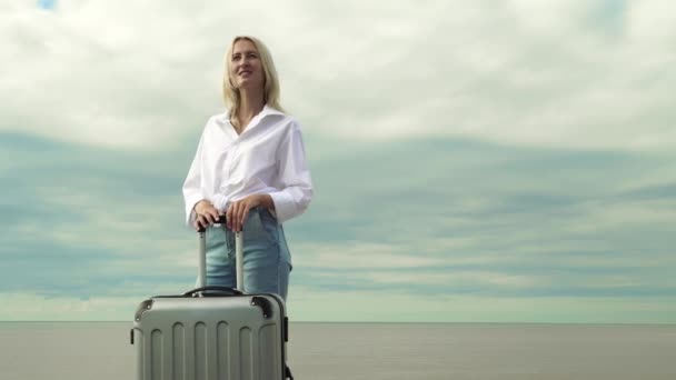 Una bella donna con una valigia sullo sfondo del mare — Video Stock