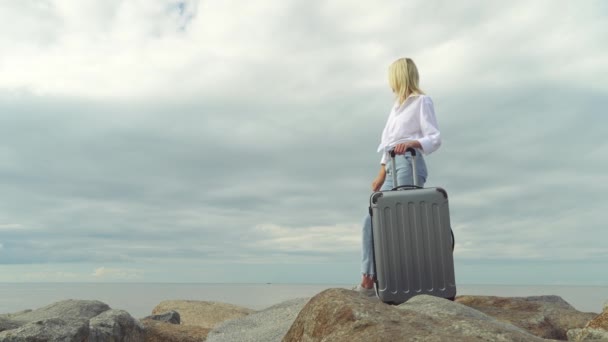 Una bella donna con una valigia sullo sfondo del mare — Video Stock