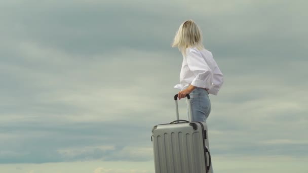 Eine schöne Frau mit einem Koffer auf dem Hintergrund des Meeres — Stockvideo