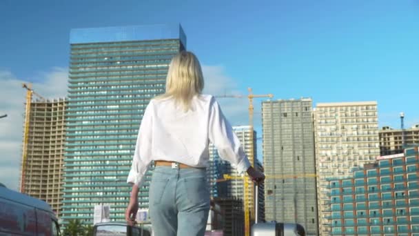 Una chica con una maleta está caminando por la ciudad.. — Vídeos de Stock