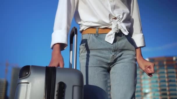 Girl with suitcase stands against background of city, tall skyscrapers — Stock Video