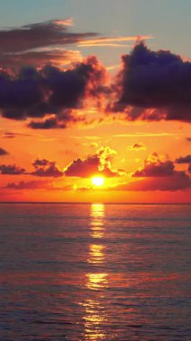 Denizdeki bulutlarda parlak turuncu bir günbatımı.