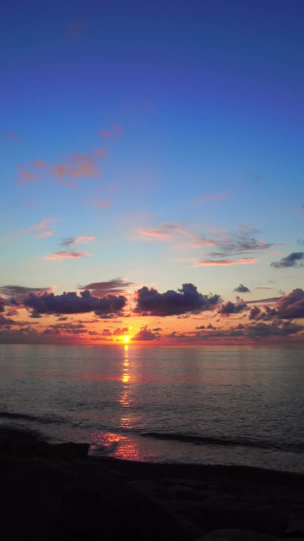 Un luminoso tramonto arancione tra le nuvole sul mare. — Video Stock