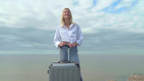 Μια όμορφη γυναίκα με μια βαλίτσα στο φόντο της θάλασσας — Αρχείο Βίντεο
