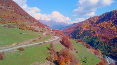 Yılanımsı dağ yolu ve ormanla sonbahar dağlarının üzerinden Drone 'la uçmak.
