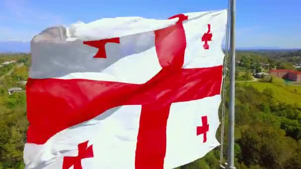 Georgiska flaggan flyger mot bakgrund snöklädda berg väg by. — Stockvideo