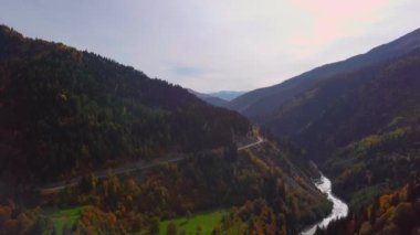 Dönek bir yolu olan dağ nehrinde bir dronun kuş bakışı görüntüsü.