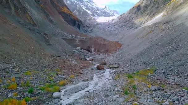 Dron vuela sobre el río entre montañas en otoño, en la distancia Glaciar Chalaadi — Vídeos de Stock