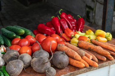 Marketteki tezgahta taze sebzelerin yakın çekimi. Domates, biber, salatalık, pancar, sarımsak, havuç, kırmızı biber.