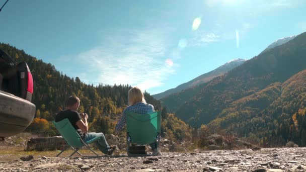 Erkekler ve kızlar katlanan koltuklarda oturup çay içip dağlara bakıyorlar. — Stok video