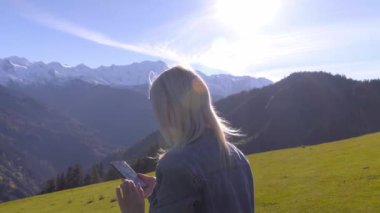 Güzel sarışın, sonbahar dağlarındaki bir manzaranın fotoğraflarını ya da videolarını çeker..