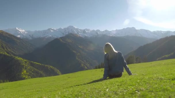 O femeie stă pe o pajişte şi se bucură de priveliştea munţilor.. — Videoclip de stoc