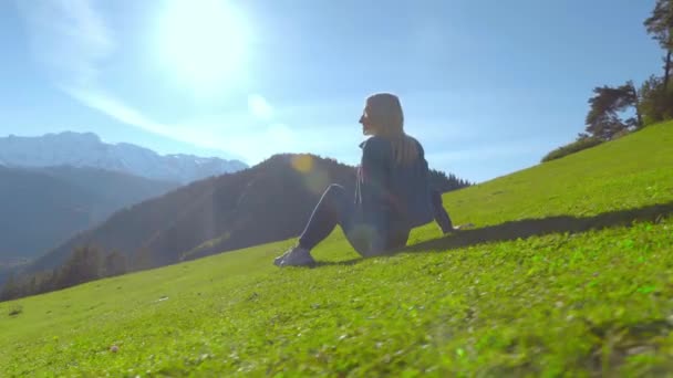 一个女人正坐在草地上欣赏群山的景色. — 图库视频影像