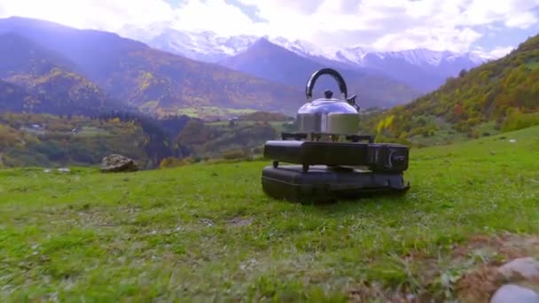 Wasserkocher steht auf einem tragbaren Campinggasherd, Wasser heizt sich auf, die Berge — Stockvideo