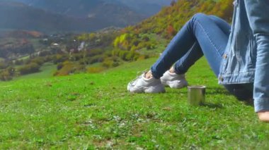 Bir kadın dağlara hayran, yanında çay ya da kahve bardağı var..