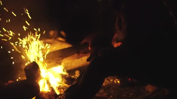 Chico joven y una chica están sentados en sillas plegables junto al fuego y hablando. — Vídeos de Stock