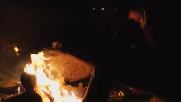 若い男と女の子が火のそばで椅子に座って話をしている. — ストック動画