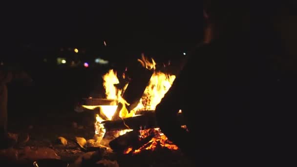 Jeune homme et une fille sont assis sur des chaises pliantes au coin du feu et parlent. — Video