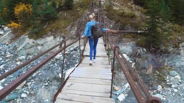 Jonge mooie slanke vrouw in een denim pak lopen op een hangbrug — Stockvideo