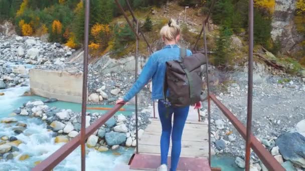 Jonge mooie slanke vrouw in een denim pak lopen op een hangbrug — Stockvideo