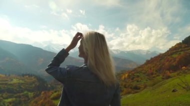 Kadın saçlarını düzleştiriyor ve sonbahar dağ manzarasının tadını çıkarıyor..