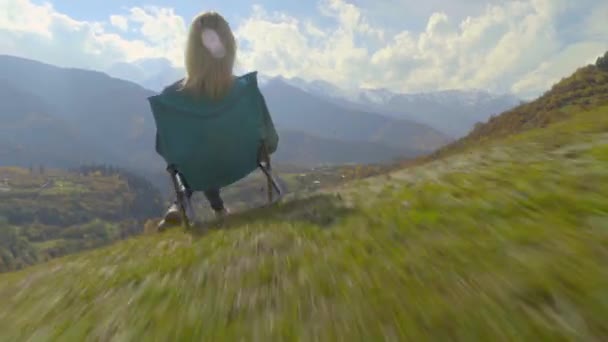 Eine Frau sitzt auf einem Stuhl und beobachtet das Bergtal im Herbst. — Stockvideo