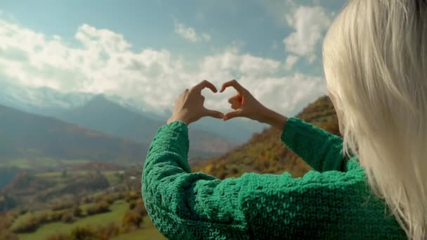 Femme en randonnée au sommet de la montagne fait cadre doigt en forme de coeur avec ses mains. — Video
