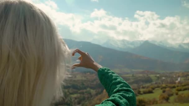 Femme en randonnée au sommet de la montagne fait cadre doigt en forme de coeur avec ses mains. — Video