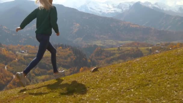 La telecamera segue una giovane bella donna che corre in salita lungo un pendio — Video Stock