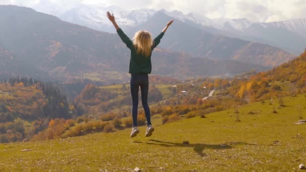 Mujer salta y aplaude contra el fondo de las montañas — Vídeos de Stock