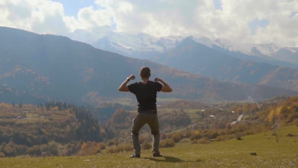 Hombre salta y aplaude sus manos contra el fondo de las montañas de otoño. — Vídeos de Stock